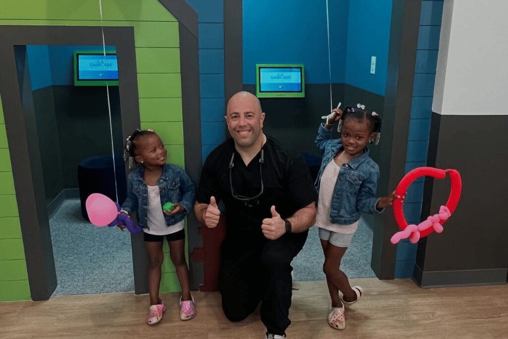Dr Anthony Sciortino smiling with two young patients